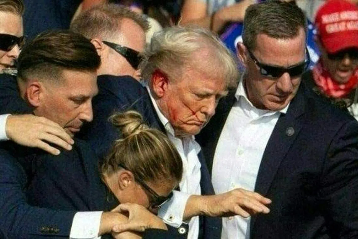 TOPSHOT - Republican candidate Donald Trump is seen with blood on his face surrounded by secret service agents as he is taken off the stage at a campaign event at Butler Farm Show Inc. in Butler, Pennsylvania, July 13, 2024. Republican candidate Donald Trump was evacuated from the stage at today's rally after what sounded like shots rang out at the event in Pennsylvania, according to AFP.
The former US president was seen with blood on his right ear as he was surrounded by security agents, who hustled him off the stage as he pumped his first to the crowd.
Trump was bundled into an SUV and driven away. (Photo by Rebecca DROKE / AFP)