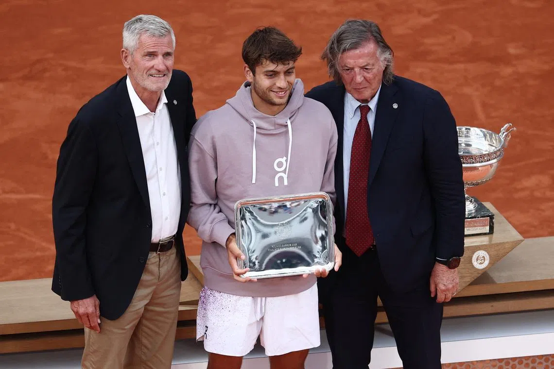 Tennis - French Open - Roland Garros, Paris, France - June 7, 2026 Italy's Flavio Cobolli poses for a photo with the runners up trophy with President of the French Tennis Federation Gilles Moretton and Former Tennis player Adriano Panatta REUTERS/Guglielmo Mangiapane