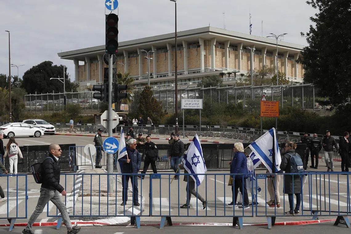 Protesters hold Israeli flags ahead of an anti-government rally next to the Israeli parliament in Jerusalem, Feb 13, 2023. 