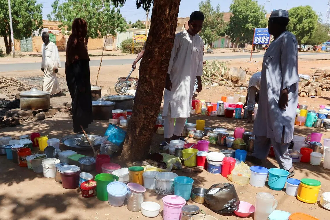 FILE PHOTO: Sudanese men stand next to empty containers in front of \"Takaya\" the charity restaurant and a community kitchen, that helps the needy Sudanese in Omdurman areas recently controlled by army during the conflict and war, during the holy month of Ramadan in the state of Khartoum, Sudan March 14, 2025. REUTERS/El Tayeb Siddig/File Photo
