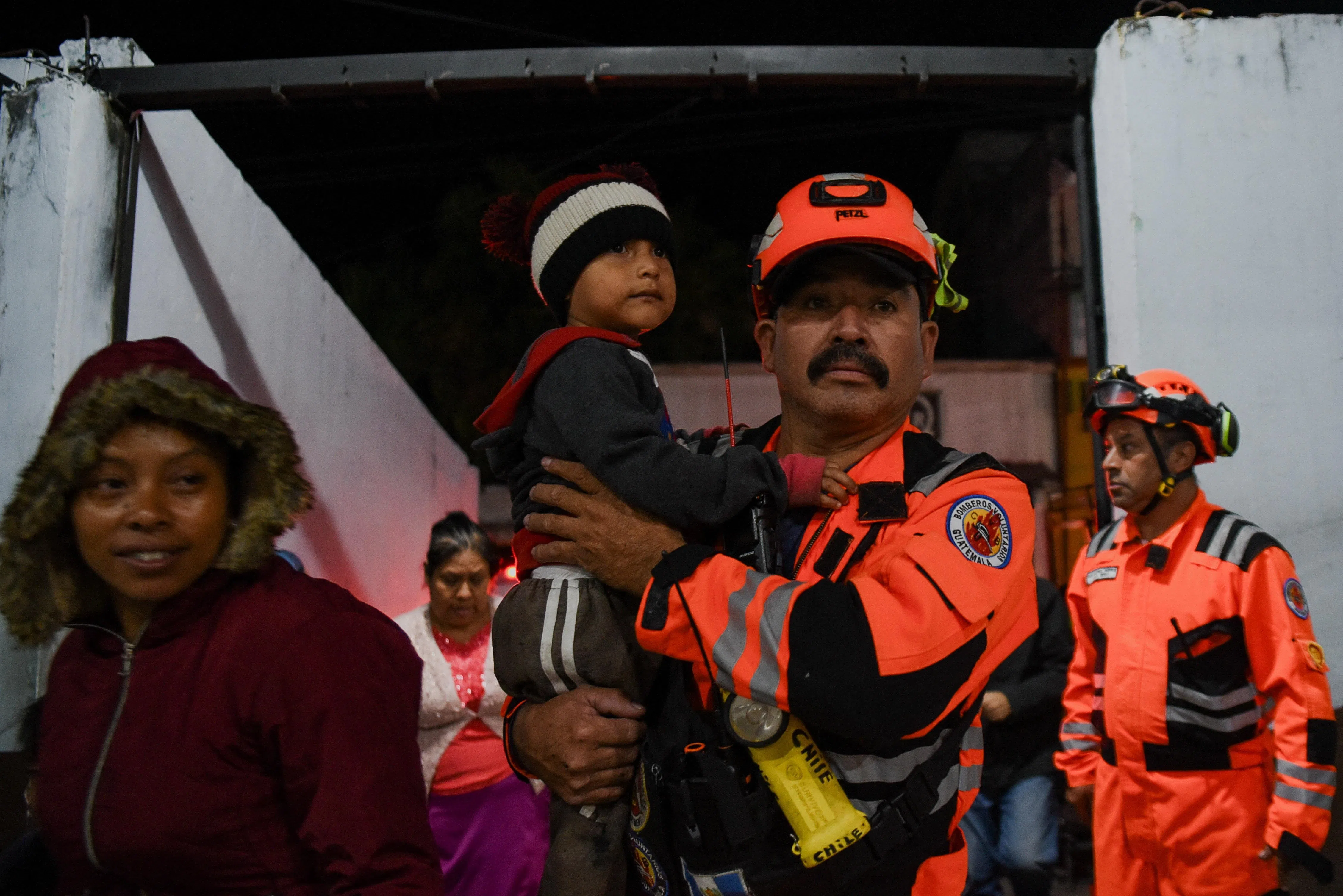 A volunteer firefighter carrying a child as they help to evacuate residents in San Juan Alotenango, Guatemala, on Aug 4.