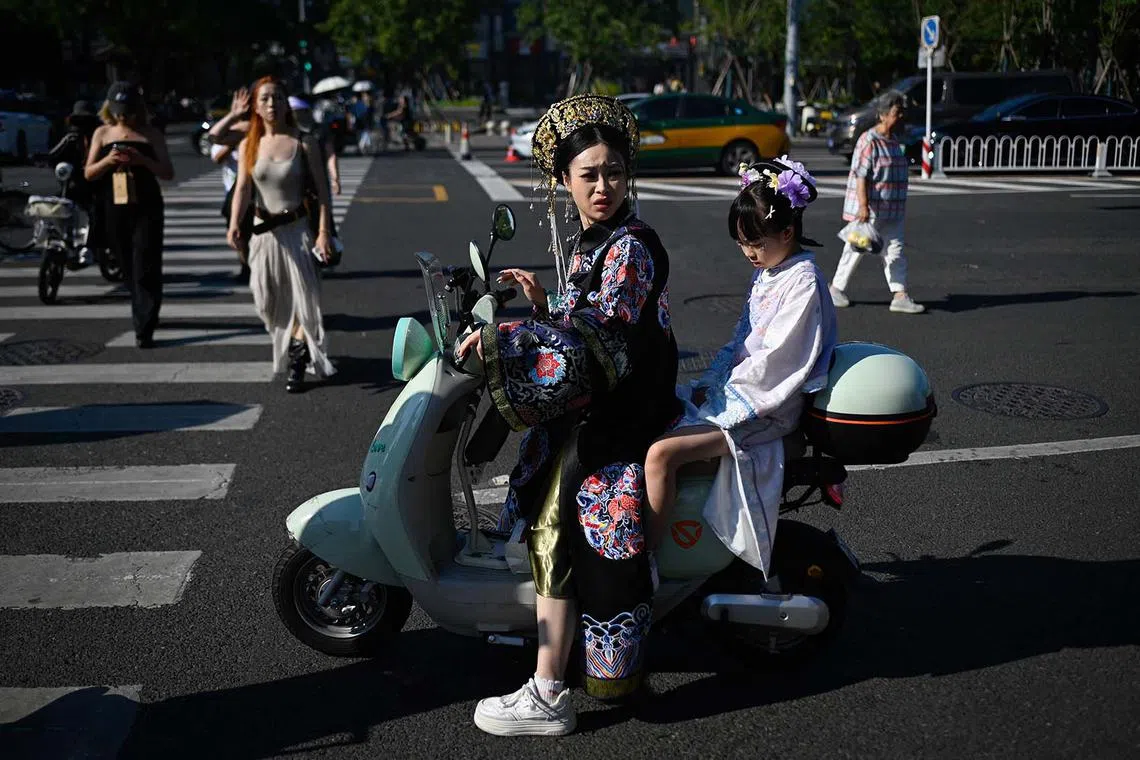 A woman and child clad in traditional attire riding an electric scooter in Beijing on Aug 25, 2025. 
