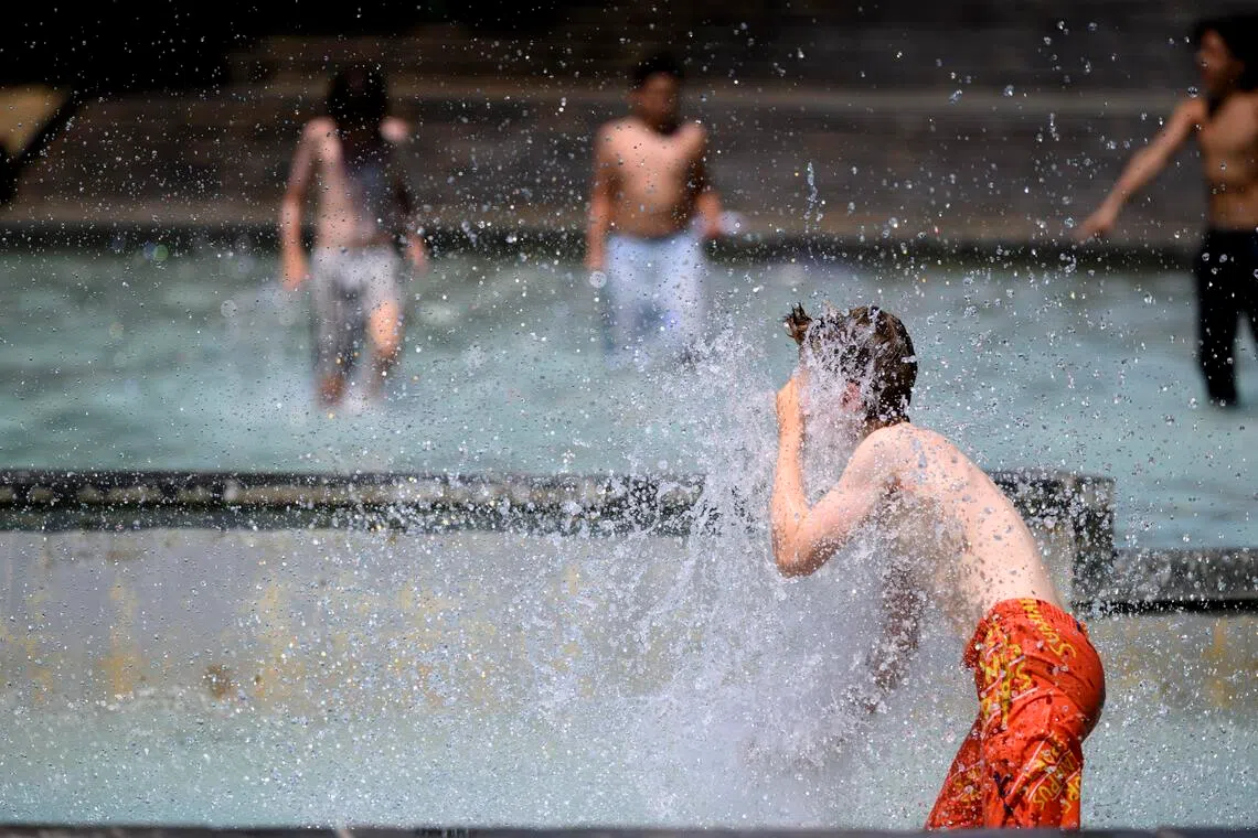 Children cool off by playing at a public fountain in Milan Park during a heat wave in Lausanne, Switzerland.