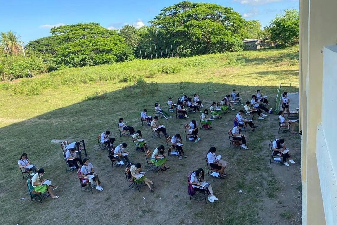 Students in the Philippines take their exams in the shadow of a school building, as a heatwave sears much of the country.