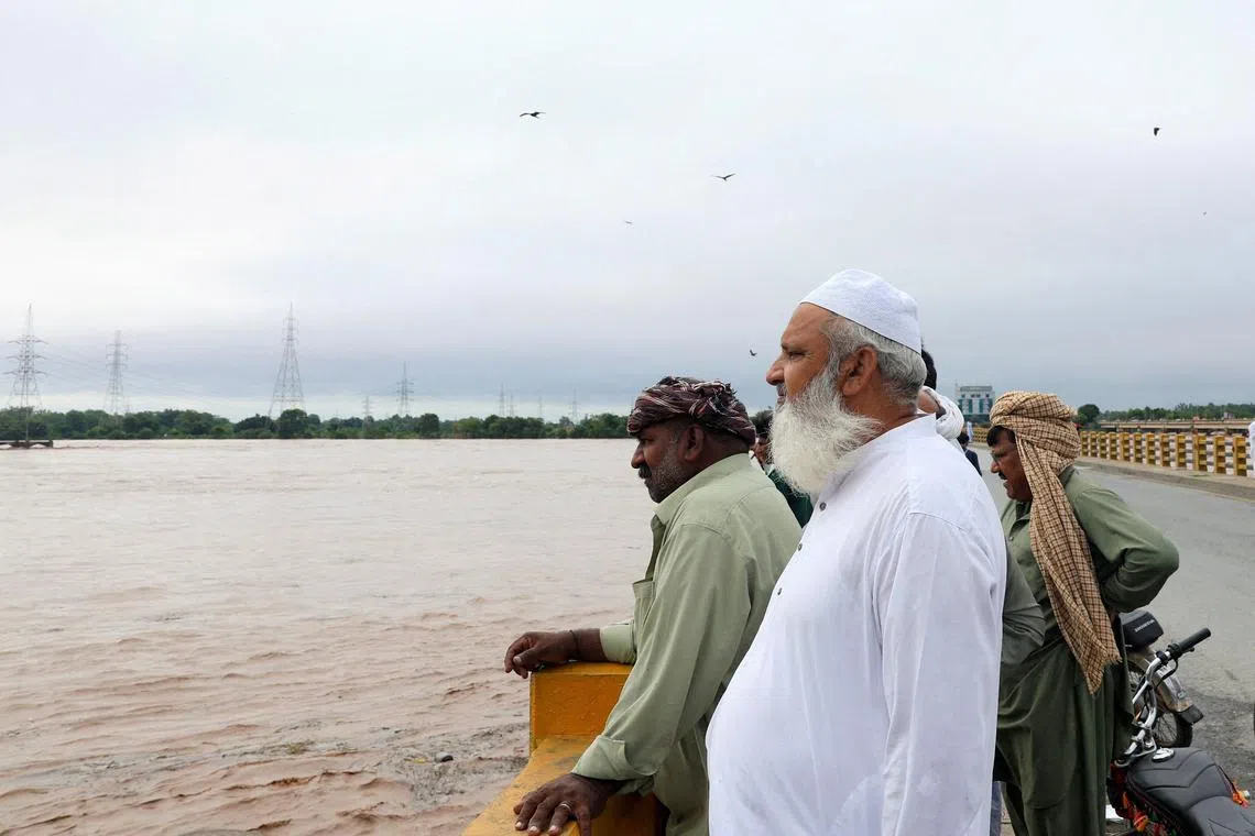Men stand on a bridge over the Chenab River, following the monsoon rains and rising water level in Wazirabad, in Punjab province, Pakistan August 27, 2025. REUTERS/Akhtar Soomro