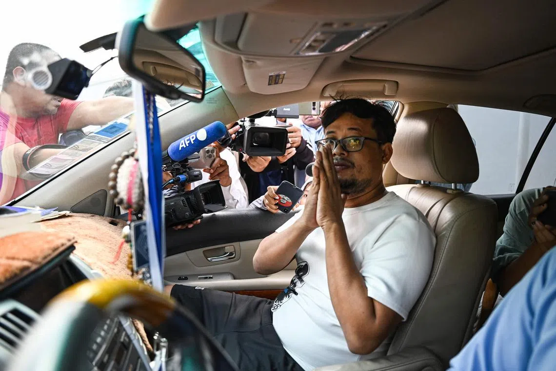 Cambodia's journalist Mech Dara gestures to media representatives as he sits in a car upon his release from Kandal Provincial prison near Phnom Penh on October 24, 2024. Award-winning Cambodian journalist Mech Dara arrested over social media posts was released on October 24, 2024 after pro-government media released a prison video showing him apologising to the country's leaders. (Photo by TANG CHHIN Sothy / AFP)