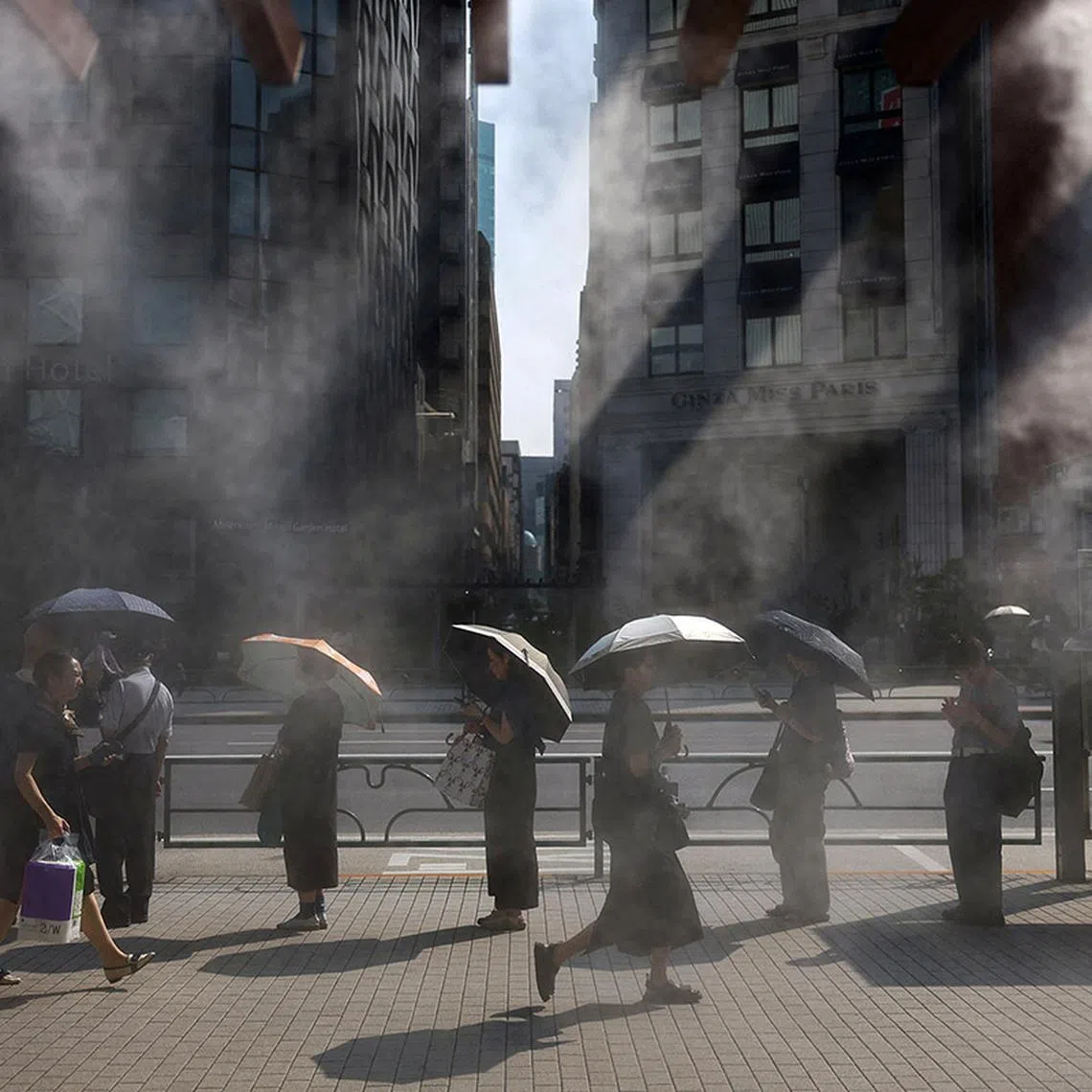 People exposed to the sun hold parasols as they wait for a bus near a cooling mist as the Japanese government issued a heatstroke alert in Tokyo and other prefectures, in Tokyo, Japan July 9, 2025. REUTERS/Issei Kato TPX IMAGES OF THE DAY
