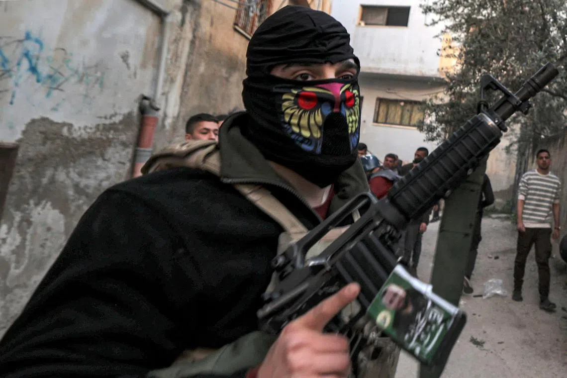 Masked Palestinian gunmen walk along an alley during an Israeli army raid on a West Bank refugee camp, on March 7, 2023.