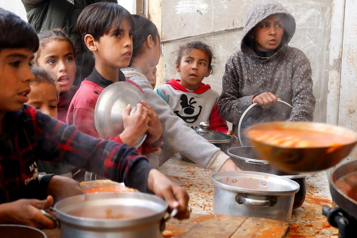Palestinian children wait to receive food cooked by a charity kitchen, during the Muslim holy month of Ramadan, in Khan Younis, in the southern Gaza Strip, March 9, 2025. REUTERS/Hatem Khaled/File Photo