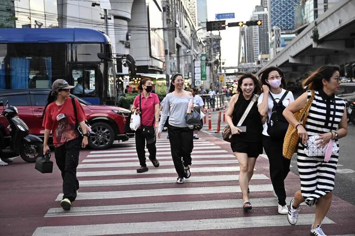 People run across a pedestrian crossing in Bangkok on June 16, 2025. (Photo by Lillian SUWANRUMPHA / AFP)