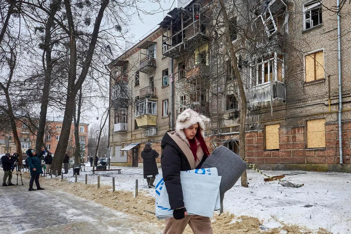 A woman carrying a blanket distributed by UN workers near the site of a Russian strike on a four-storey residential building in Kharkiv, northeastern Ukraine, on Jan 24.