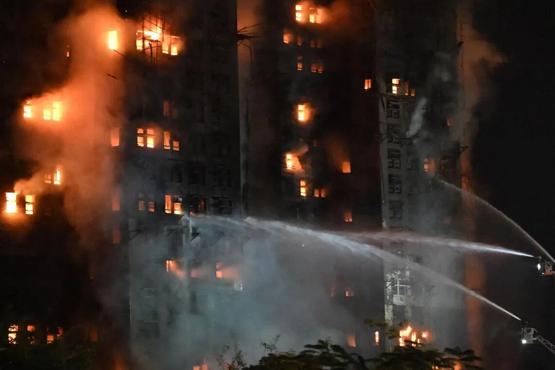 TOPSHOT - Firefighters spray water during a major fire at the Wang Fuk Court residential estate in Hong Kong's Tai Po district on November 26, 2025. At least four people were killed when a fire engulfed several high-rise blocks in a Hong Kong residential estate on November 26, the government said, with media reporting that some residents were trapped inside. (Photo by Peter PARKS / AFP)