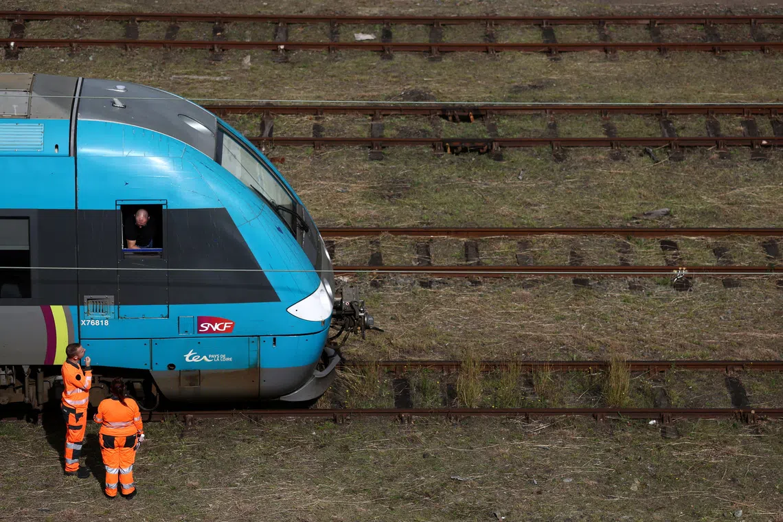 FILE PHOTO: Workers stand next to a SNCF regional train at the railway station in Nantes two days before a strike by French state-owned railway SNCF workers, France, September 16, 2025. REUTERS/Stephane Mahe/File Photo