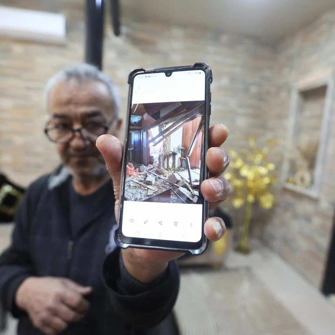 Khiam resident, Hussain Khrais shows a picture on his phone of his home before it was rebuilt after being damaged during the latest hostilities between Israel and Lebanon, in Khiam village, near the border with Israel, southern Lebanon, February 19, 2026. REUTERS/Aziz Taher