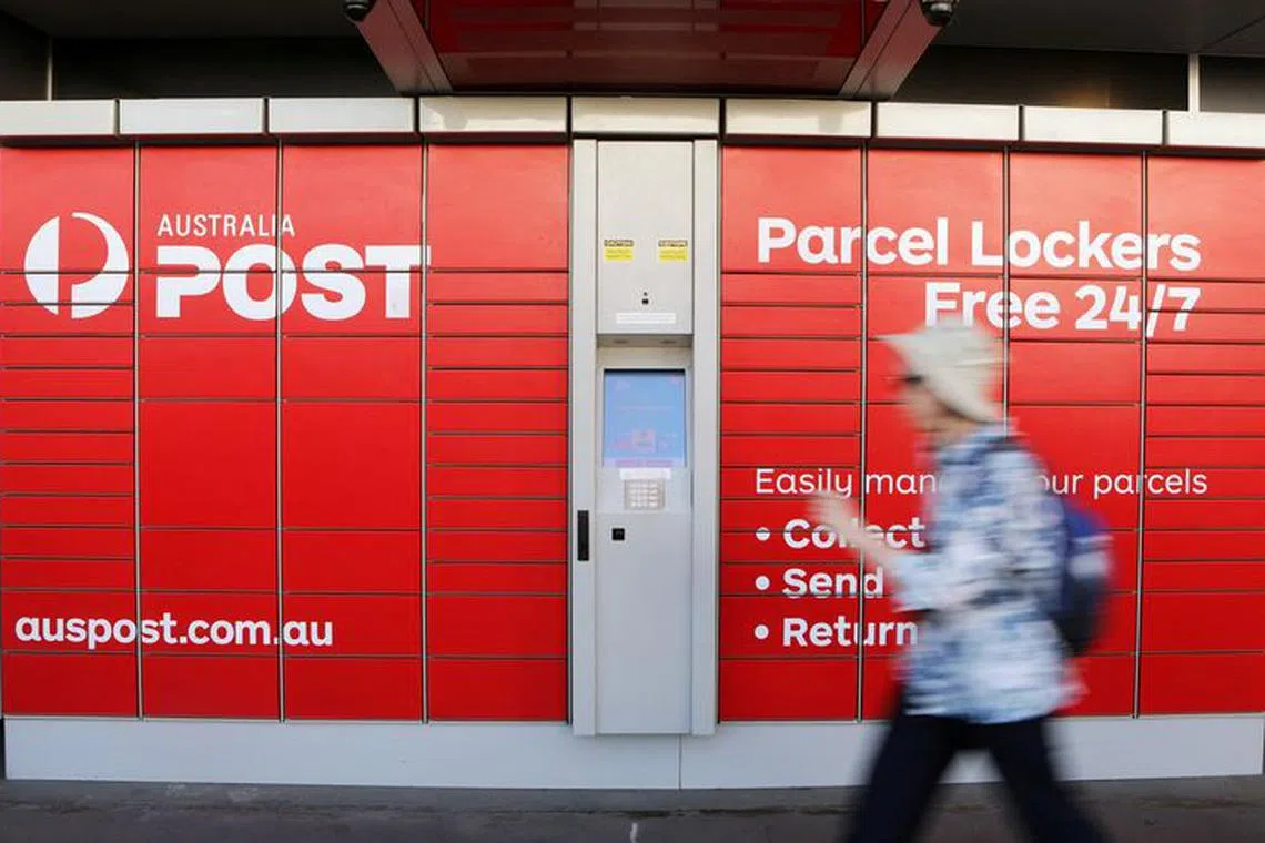 FILE PHOTO: A woman walks past Australia Post parcel lockers in Sydney, Australia, February 8, 2018. REUTERS/Daniel Munoz/File Photo