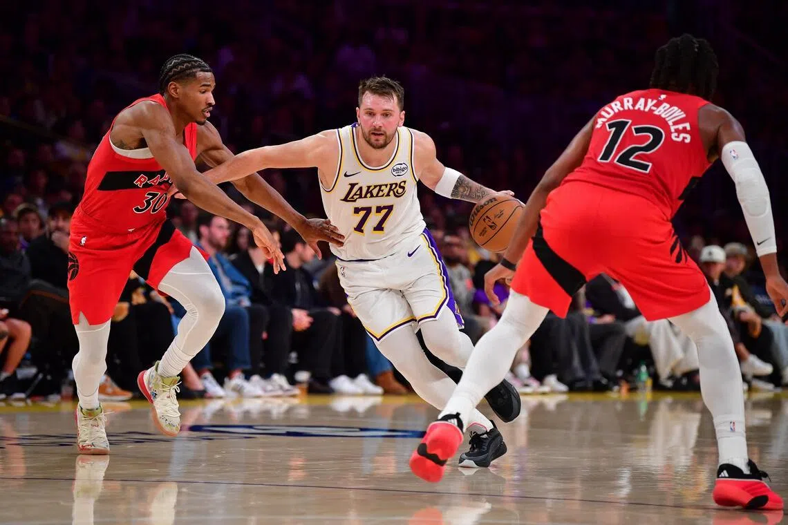 Los Angeles Lakers guard Luka Doncic moves the ball against Toronto Raptors guard Ochai Agbaji and forward Collin Murray-Boyles during the first half at Crypto.com Arena. 