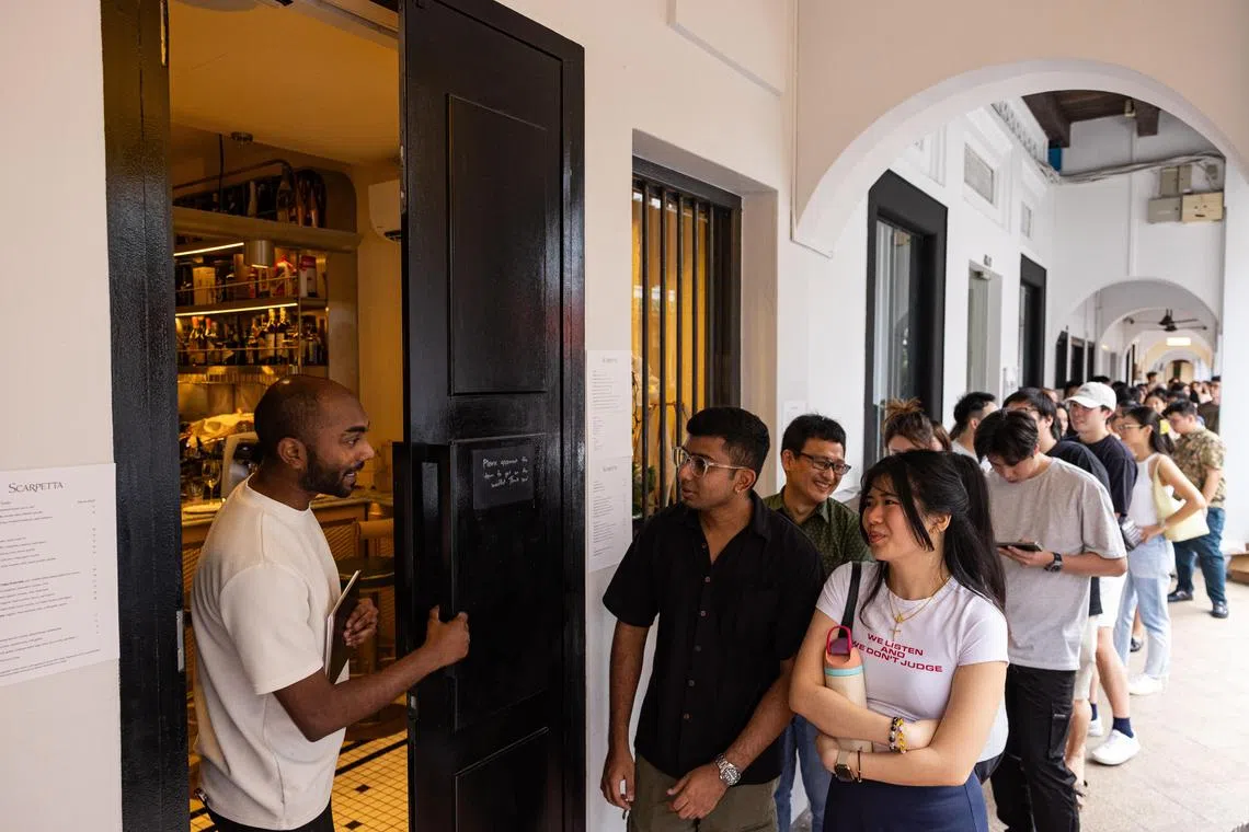 Mr Theeviyan Raja (left), 28, a front-of-house staff member at Scarpetta, welcomes diners as the restaurant opens for dinner. By 6pm, around 80 customers had joined the queue.