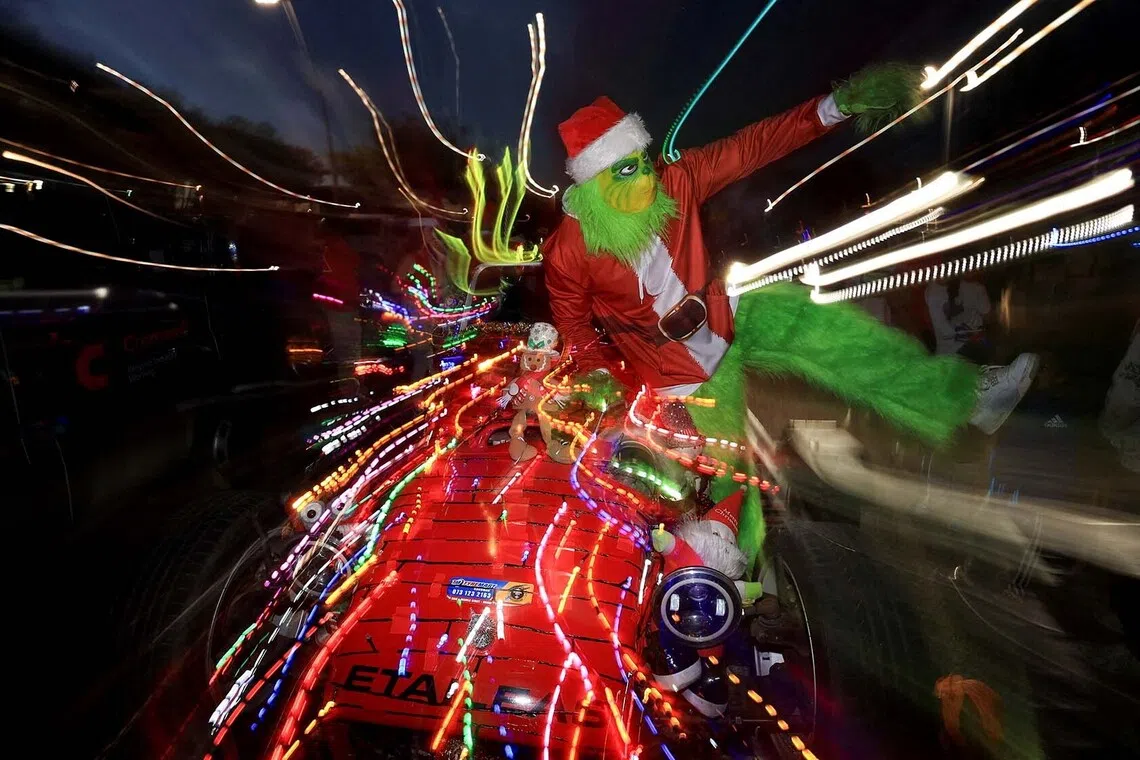 A man dressed as the Grinch poses on a car decorated with Christmas lights during Christmas season in Cape Town, South Africa, December 14, 2025. Picture taken with a low shutter speed. REUTERS/Esa Alexander TPX IMAGES OF THE DAY