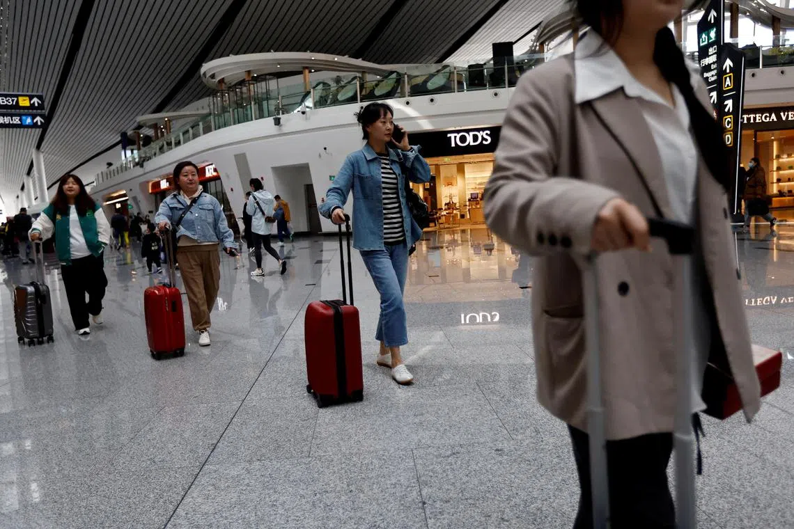 FILE PHOTO: Travellers walk with their suitcases at Beijing Daxing International Airport in Beijing, China April 24, 2023. REUTERS/Tingshu Wang/File Photo