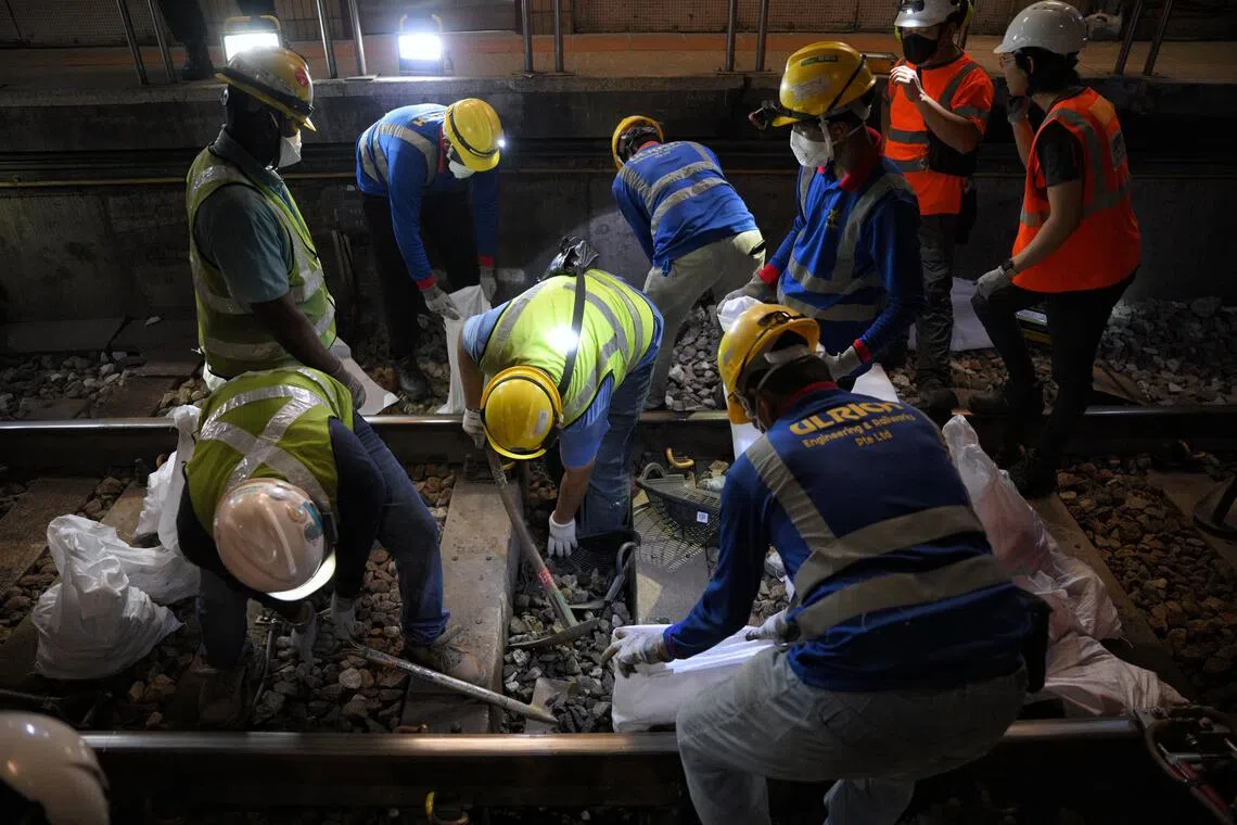 Workers digging up the old ballast in between sleepers during the ballast renewal process at Bishan MRT Station in the early hours of Dec 11.