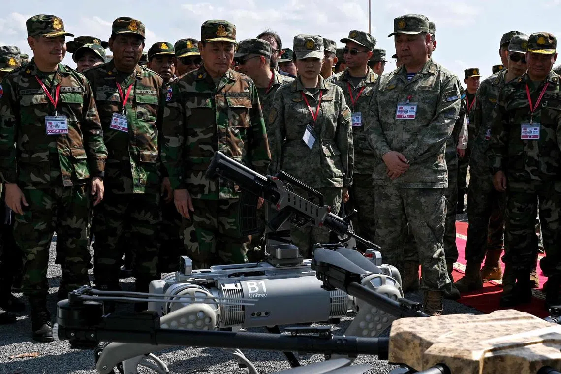 General Vong Pisen (centre left) and Chinese People's Liberation Army (PLA) Southern Theatre Command's Gao Xiucheng (centre right) attend a demonstration of a machine gun equipped "robodog".