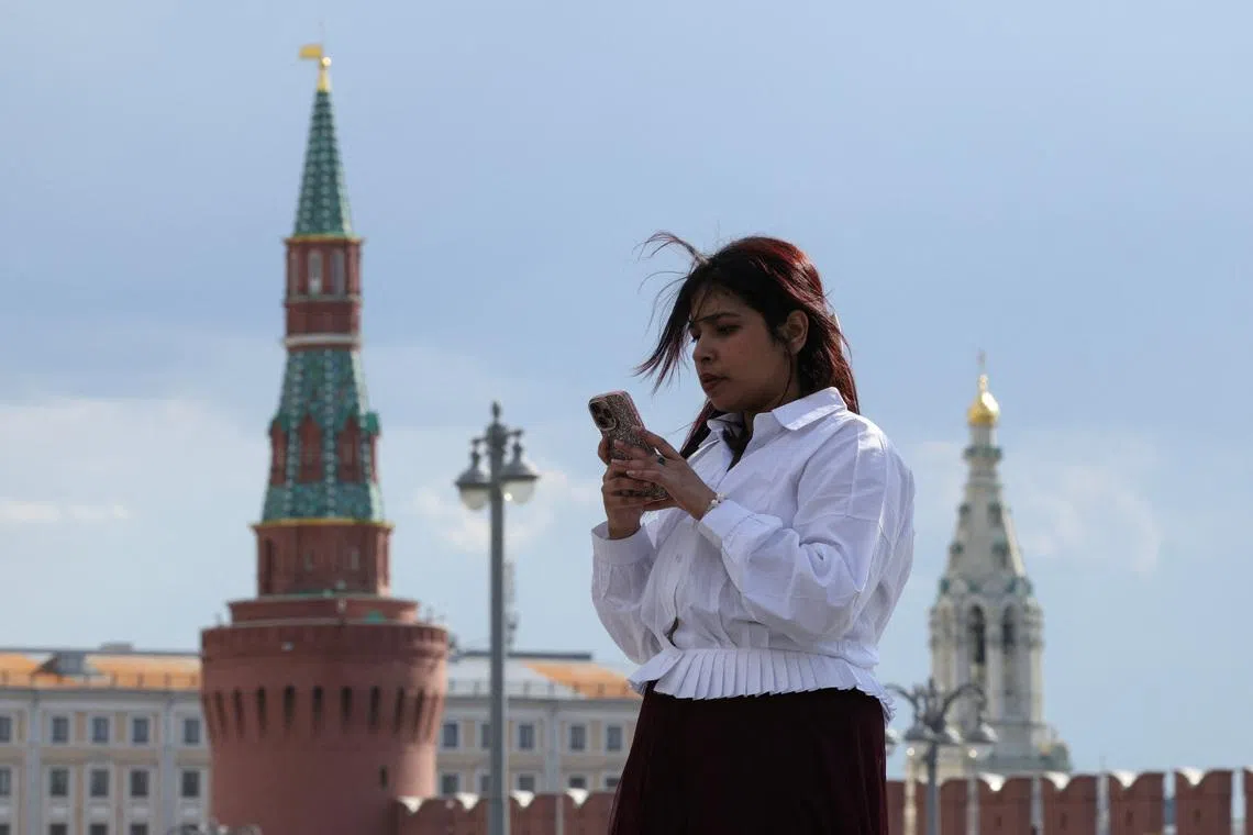 A woman checks her mobile phone near the Kremlin wall in central Moscow, Russia, May 4, 2026. REUTERS/Ramil Sitdikov