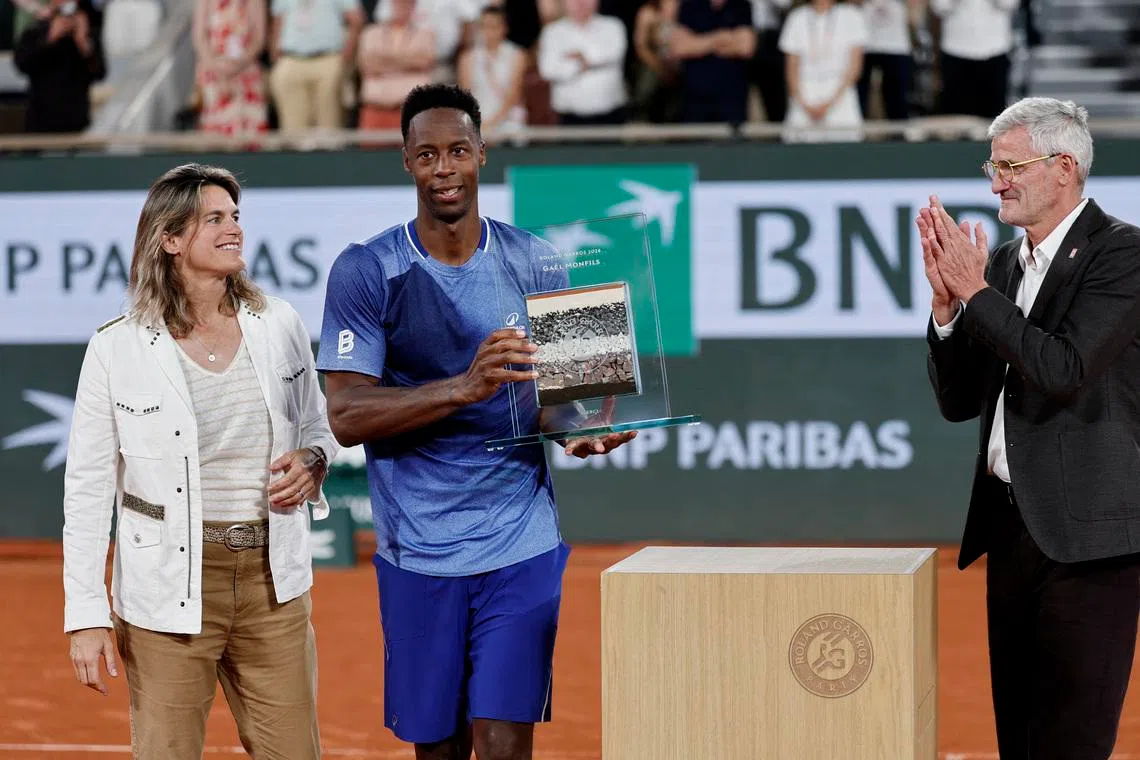 France's Gael Monfils poses with an award from Roland Garros after losing his first round match against France's Hugo Gaston.