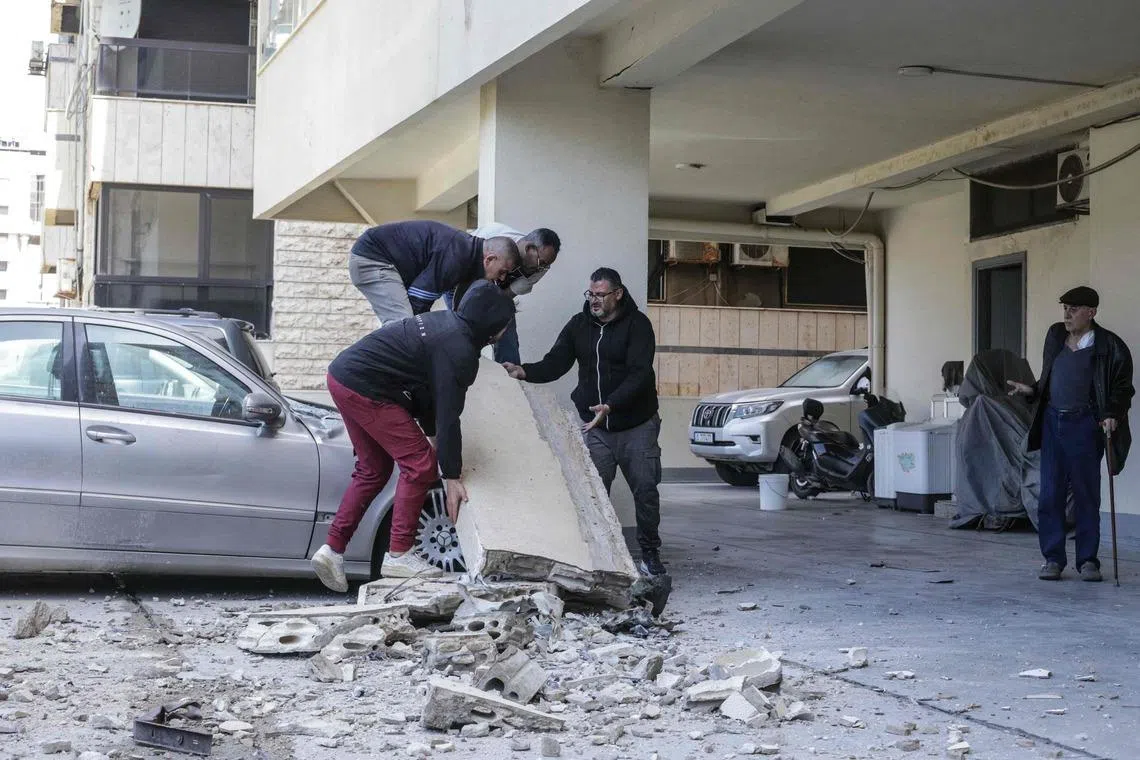 Residents trying to move a block of concrete from a car at the site of an Israeli strike in Beirut on March 28. Three journalists were reported killed in a strike in south Lebanon on the same day.