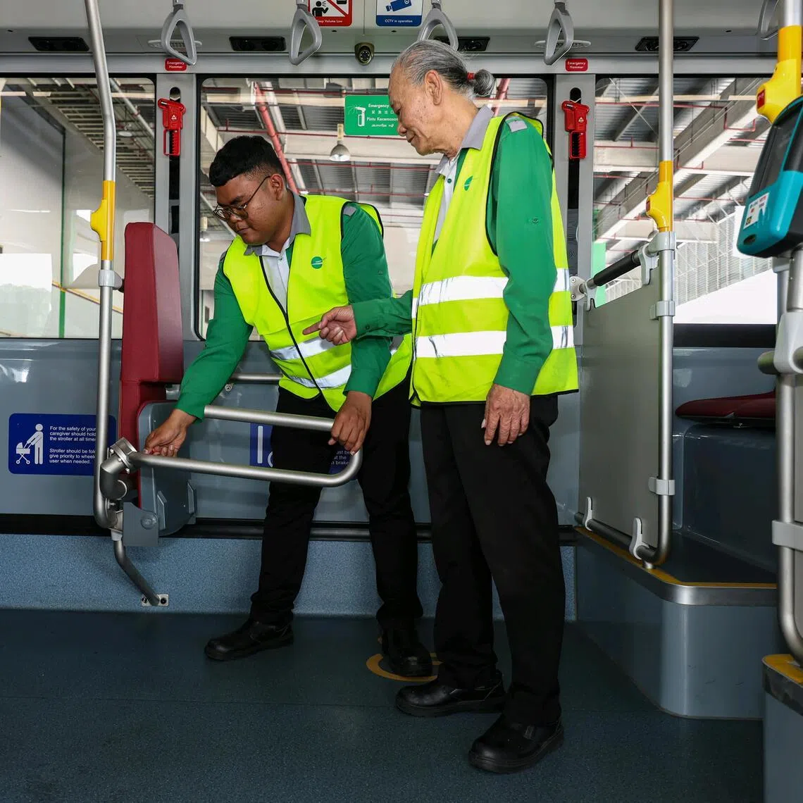Mr Alex Poon, 74, guiding his younger colleague Mr Mohammad Zulhilmi Arif, 28, in conducting routine checks on a bus at Bulim Bus Depot. 