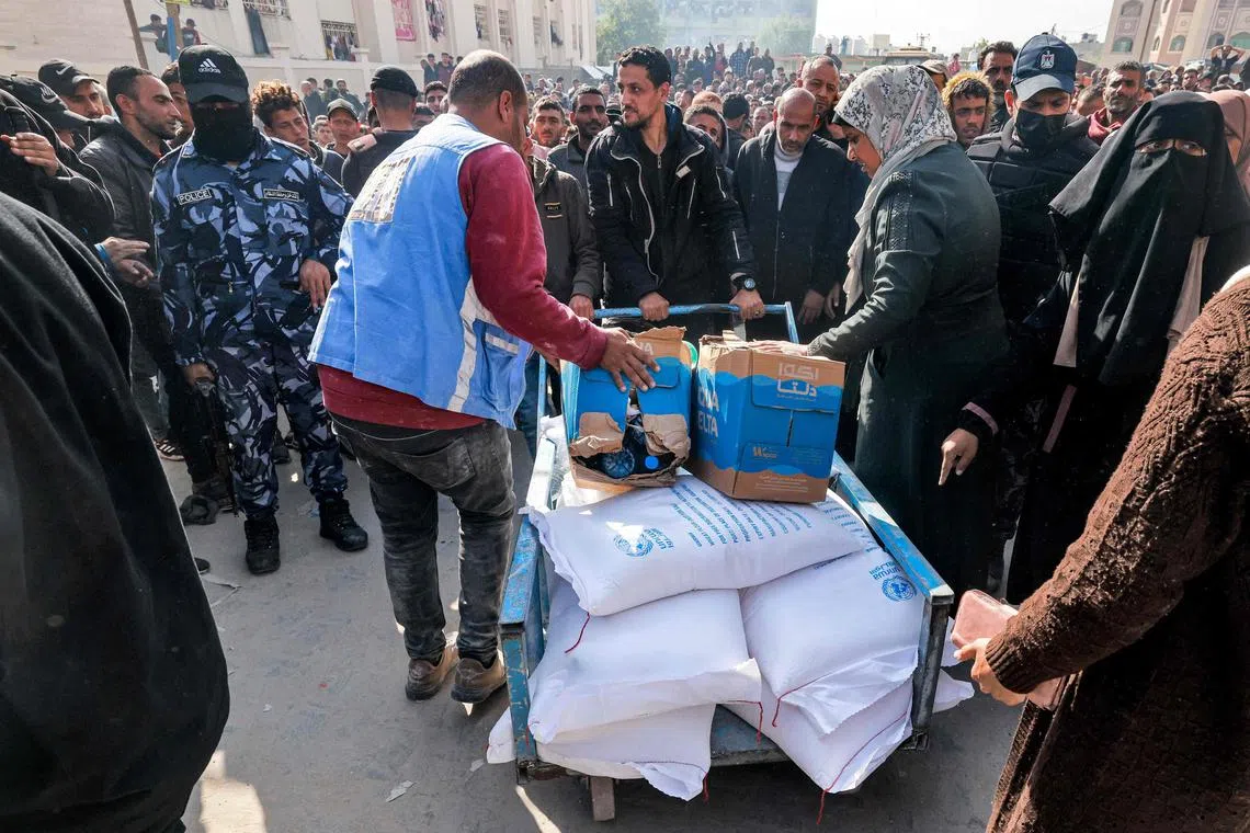 Workers from the United Nations Relief and Works Agency for Palestine Refugees hand out flour rations and other supplies to people on Dec 12.