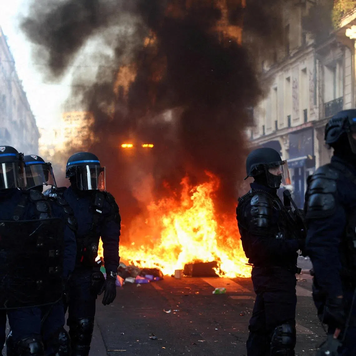 Police officers in riot gear stand guard, during civil unrest, the day after a national day of demonstrations against the cost of living and rising fuel prices in Paris on Oct 18.