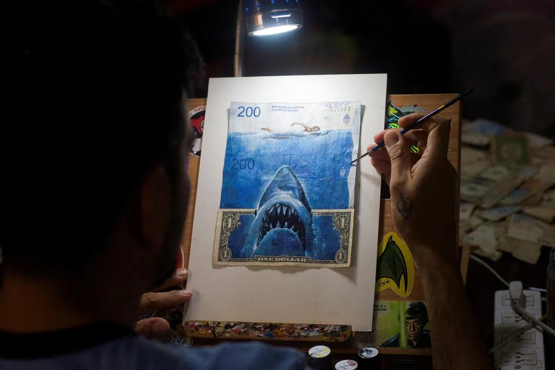 Artist Sergio Diaz intervenes Argentine pesos bills and a US dollar bill depicting Steven Spielberg's movie "Jaws" as a parody of Argentina's ever-increasing inflation, in Salta, Argentina