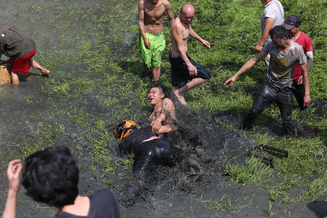 People catching fishes and ducks at a rice field during a tourism event in China's southwestern Guizhou Province on May 04, 2023.