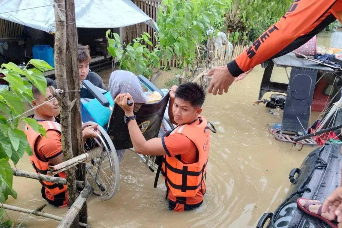Philippine Coast Guard personnel rescue a wheelchair-bound woman from her flooded home in hard-hit Bicol region.