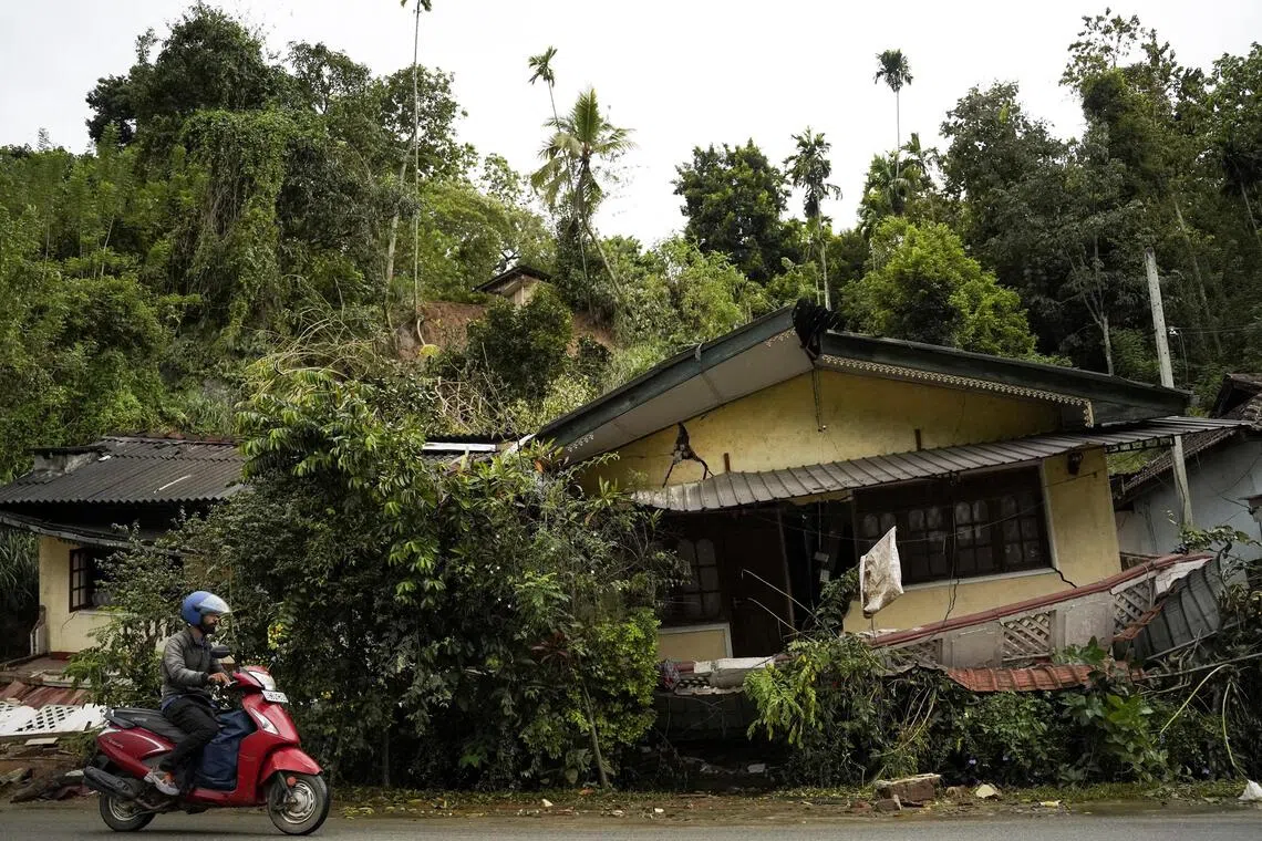 A man rides a scooter past a damaged house following Cyclone Ditwah, at Kandekumbura in Kandy District, Sri Lanka, on Dec 5. 