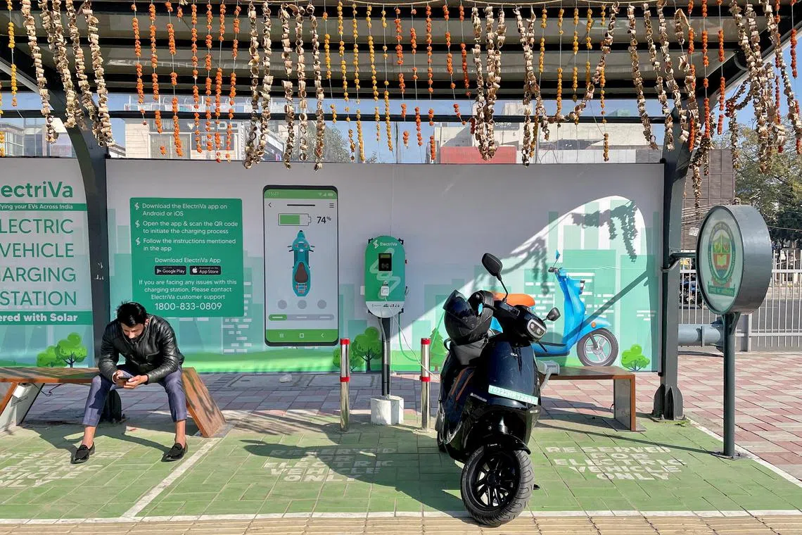 FILE PHOTO: A man waits while recharging his Ola electric scooter at an electric vehicle charging station in New Delhi, India, February 12, 2022. Picture taken February 12, 2022. REUTERS/Aditi Shah/File Photo
