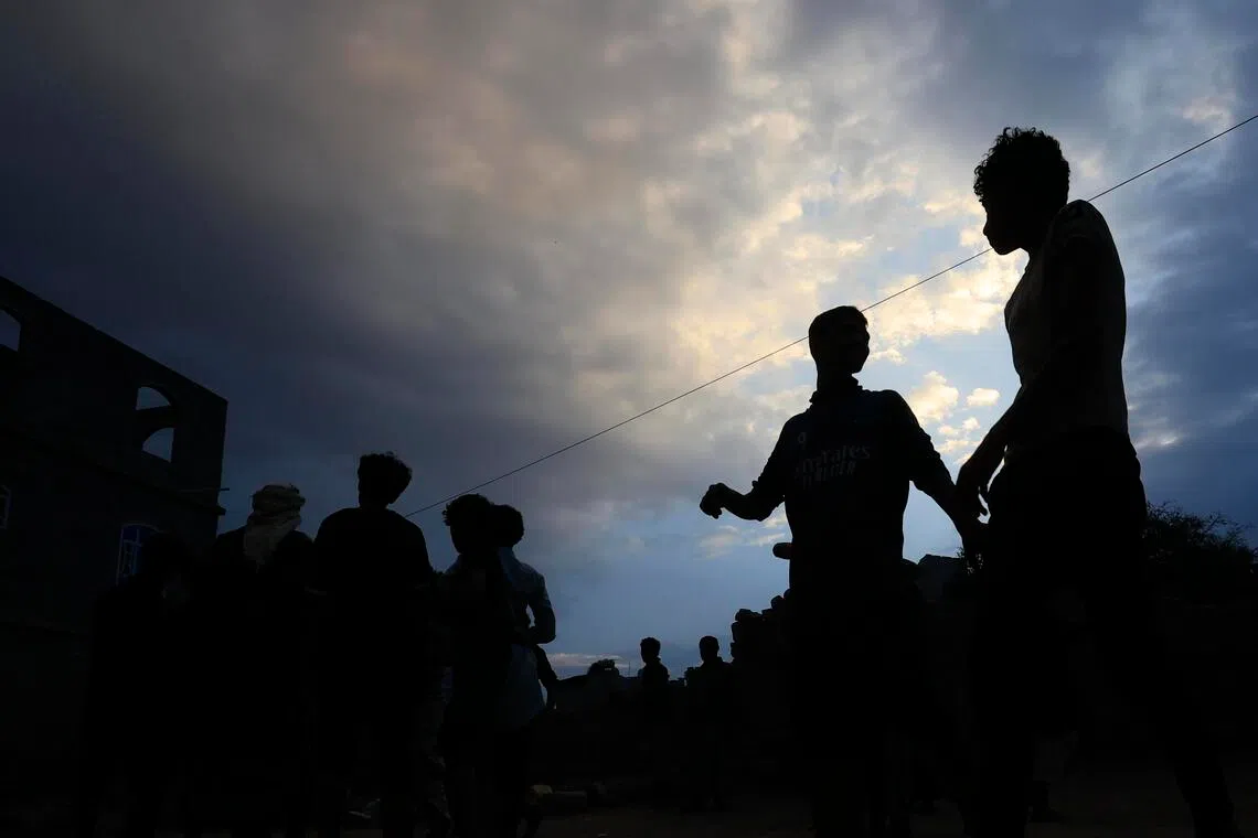 Silhouettes of a crowd of people against a cloudy sky.