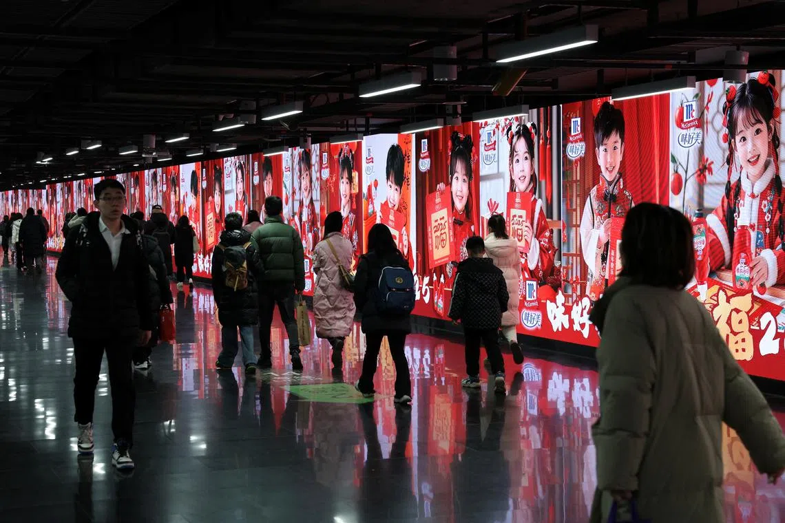 FILE PHOTO: People walk in front of billlboards in a metro station in Shanghai, China, January 16, 2025. REUTERS/Go Nakamura/File Photo