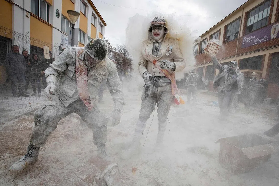 Revellers dressed in mock military garb take part in "Els Enfarinats" flour and eggs battle in the southeastern Spanish town of Ibi on December 28, 2025. In this 200-year-old traditional winter festival, the participants --known as Els Enfarinats (those covered in flour)-- dress in military clothes and stage a mock coup d'etat as they battle using flour, eggs and firecrackers outside the town hall as part of the celebrations of the Day of the Innocents, a traditional day in Spain for pulling pranks. (Photo by Jaime REINA / AFP)