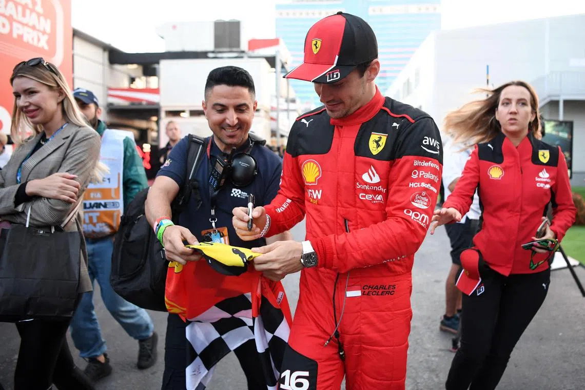 Ferrari's Monegasque driver Charles Leclerc signs autographs to fans after the qualifying session for the Formula One Azerbaijan Grand Prix at the Baku City Circuit in Baku on April 28, 2023. (Photo by NATALIA KOLESNIKOVA / AFP)