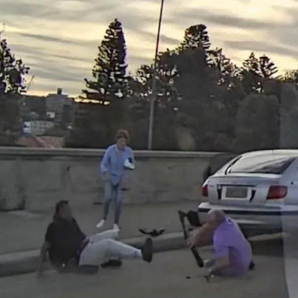 A screenshot from a dashcam clip shows a man falling down after attempting to disarm one of the gunmen behind the Bondi Beach mass shooting.

