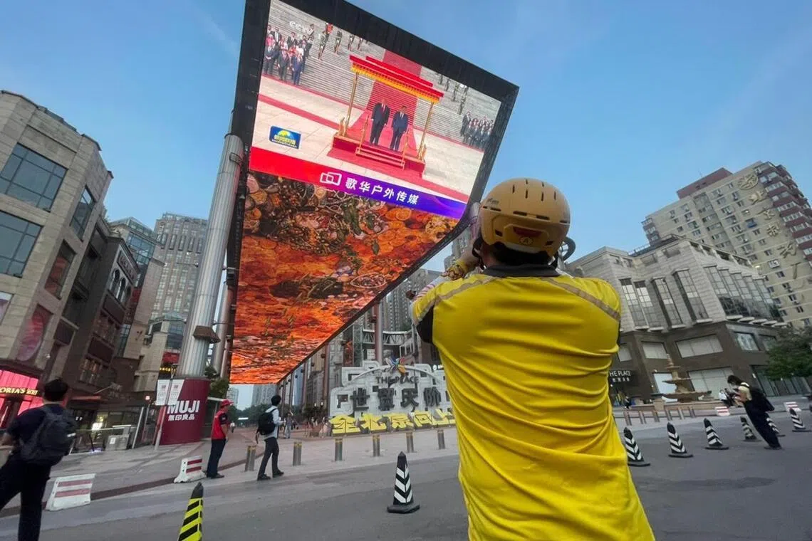 A passer-by stops to take photos of the LED screen in downtown Beijing showing coverage of US President Donald Trump’s visit to Beijing.   