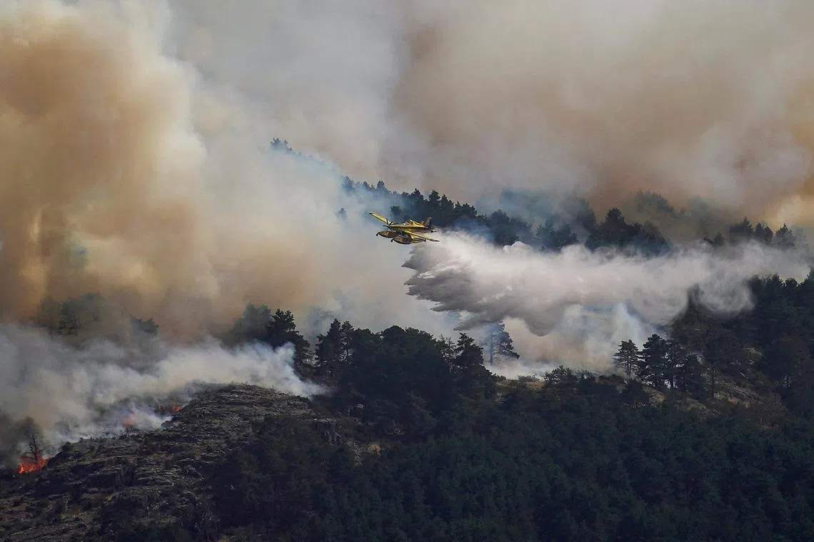 An airplane release water above the wildfire of La Mierla in Condemios de Arriba, Guadalajara, Spain July 22, 2026. REUTERS/Ana Beltran