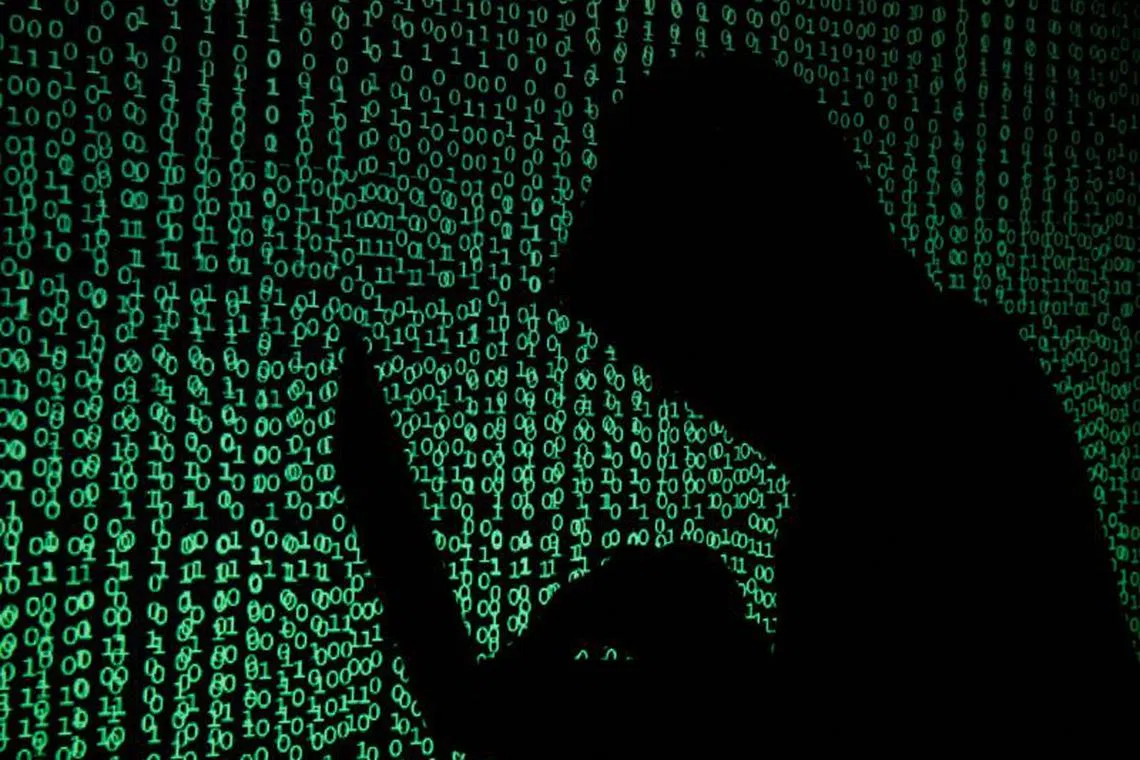 FILE PHOTO: A hooded man holds a laptop computer as cyber code is projected on him in this illustration picture taken on May 13, 2017. REUTERS/Kacper Pempel/Illustration/File Photo