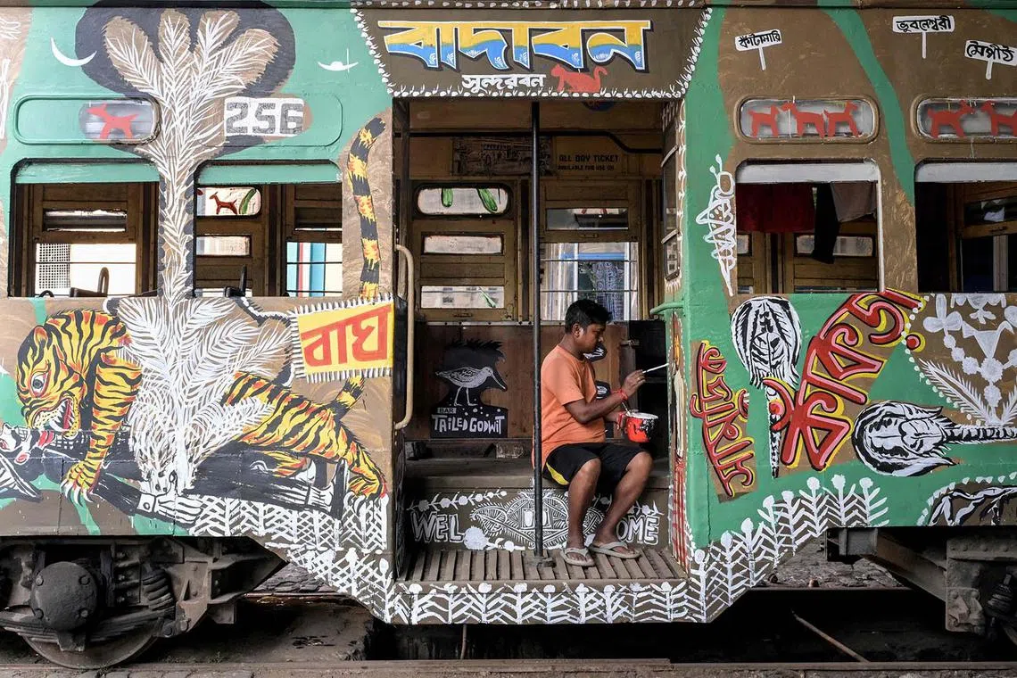 TOPSHOT - An artist paints a tram with the theme of Sundarbans, the largest mangrove forest, as a way to raise awareness of the consequences of climate change and the need for eco-friendly modes of transportation to protect the environment, in Kolkata on March 27, 2025. (Photo by Dibyangshu SARKAR / AFP)