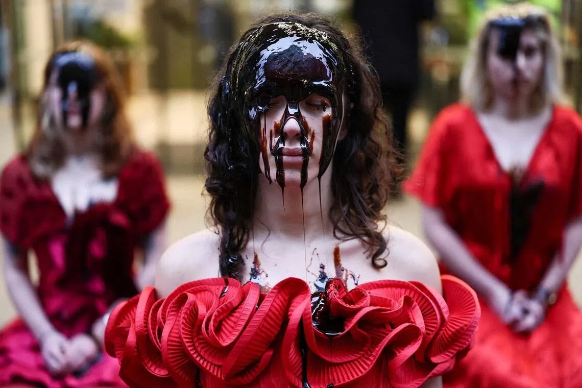 Activists wearing red rose dresses with faces covered in treacle sitting outside Equinor's offices staging an oil spill protest, as the UK Government's decision on whether to approve or reject the Rosebank oilfield is now imminent, in London, Feb 2, 2026. 