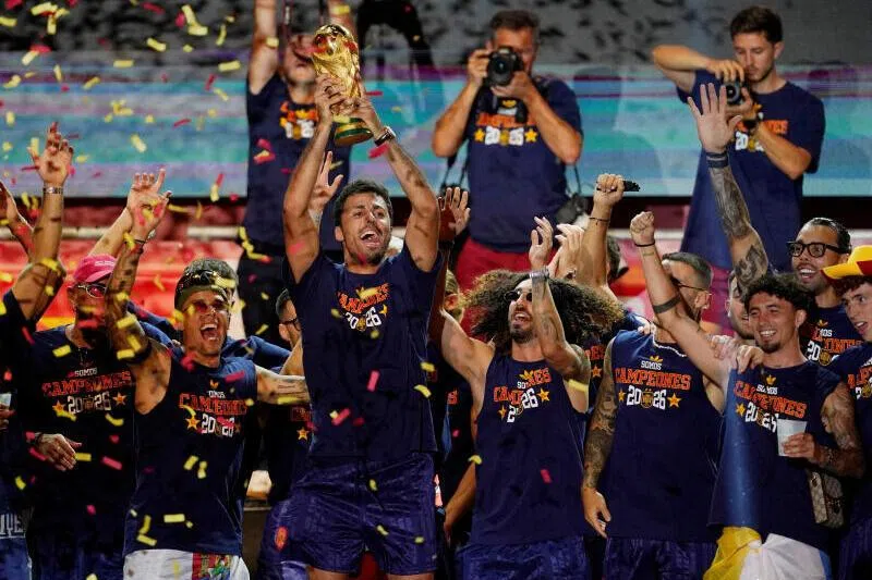 Spain’s Rodri celebrates with the World Cup trophy and teammates on stage at Cibeles Square in Madrid.