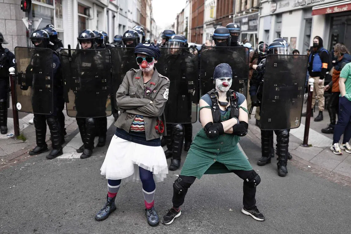 Protesters dressed as clowns posing in front of French police in riot gear as they take part in a demonstration on May Day (Labour Day), to mark the international day of the workers, more than a month after the government pushed an unpopular pensions reform act through parliament, in Lille, northern France, on May 1, 2023. 