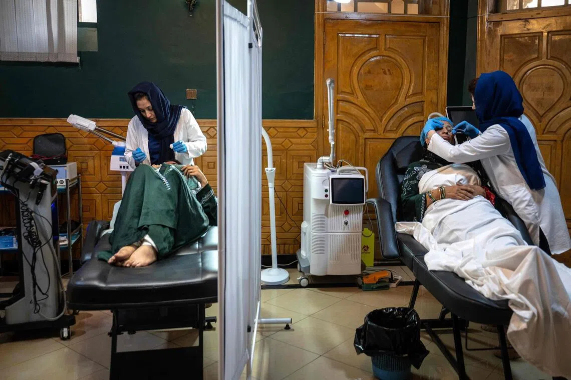 In this photograph taken on September 3, 2025, members of a medical staff attend Afghan women at a beauty clinic in Kabul. Decked with fake crystal chandeliers and velvet sofas, cosmetic surgery clinics in Afghanistan's capital are a world away from the austerity of Taliban rule, where Botox, lip filler and hair transplants reign. (Photo by Wakil KOHSAR / AFP) / To go with 'Afghanistan-Social-Cosmetic-Surgery' , REPORTAGE by Claire GOUNON