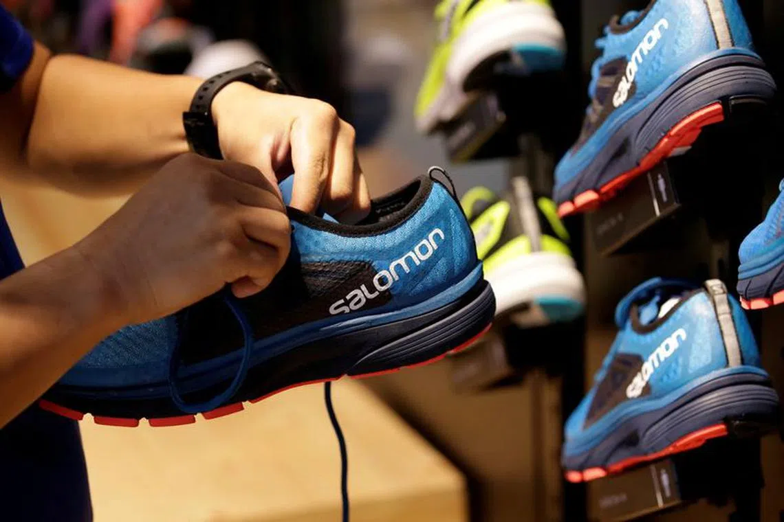 FILE PHOTO: A shop assistant holds a shoe at a Salomon store in Beijing, China August 10, 2018. Picture taken August 10, 2018. REUTERS/Jason Lee/File Photo